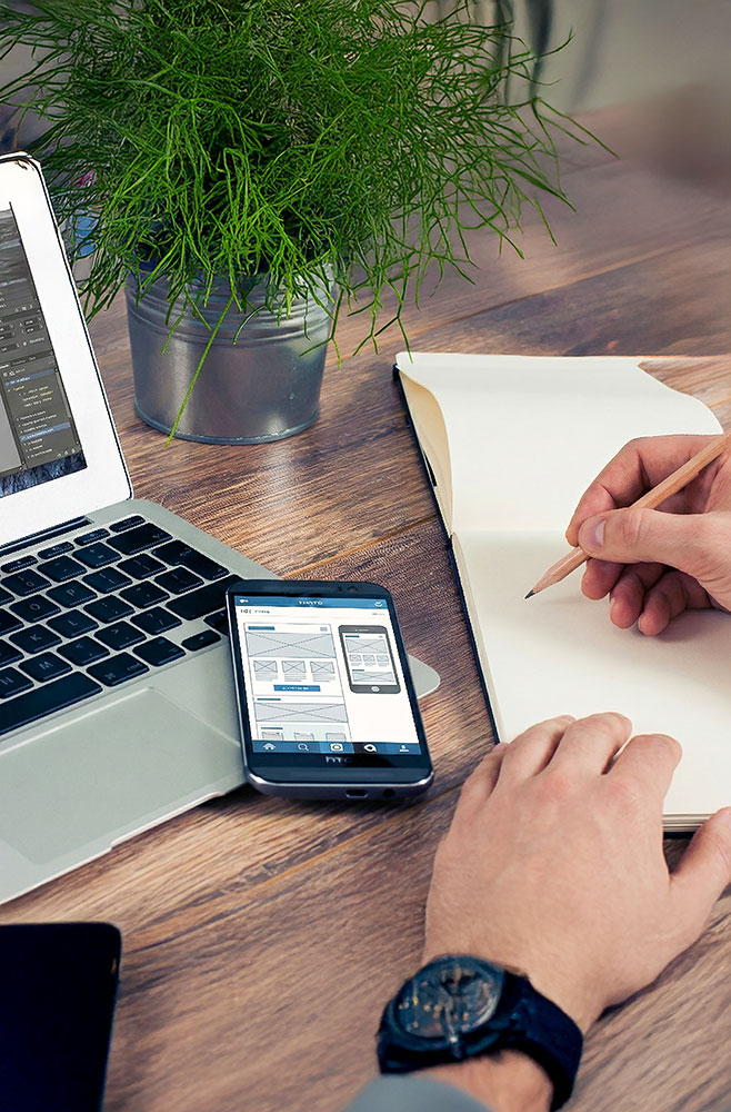 Thomas Köhn von TK Mediendesign am Schreibtisch beim Planen einer Website – zeigt die Kombination aus Notizblock (Strategie) und Laptop/Smartphone (Umsetzung).